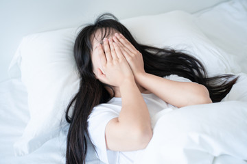 sleepy asian woman hide her eye on bed warped pillow