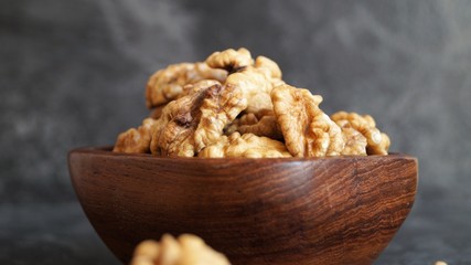 walnut kernels in a wooden dish on a black background
