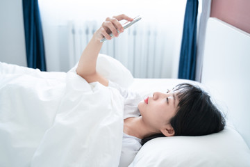 asian young woman play cellphone on the bed