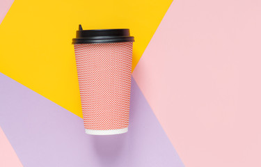 paper coffee cups lie on a bright pink background with a yellow lilac with a place for the inscription close up flat lay
