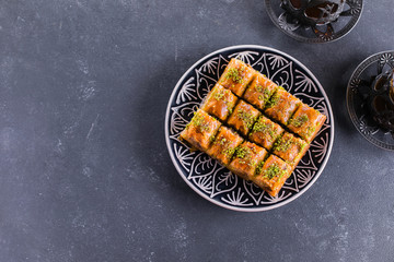 Baklava. Ramadan Dessert. Traditional Arabic dessert with nuts and honey, cup of tea on a concrete table. Top view, copy space