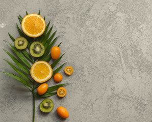 Fresh citrus fruits on green palm leaf on concrete background.Top view.
