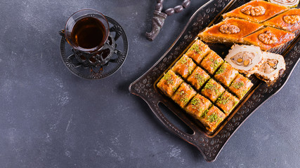 Assortment of oriental sweets. Baklava and two cups of tea on a blue concrete table. Top view, copy...