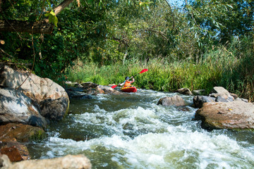 sport woman in the helmet on the kayak in the river with white water