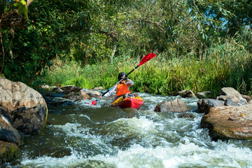 sport woman in the helmet on the kayak in the river with white water