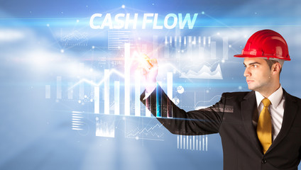 Handsome businessman with helmet drawing CASH FLOW inscription, architecture business plan concept