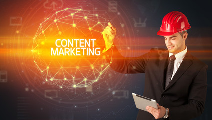 Handsome businessman with helmet drawing CONTENT MARKETING inscription, social construction concept