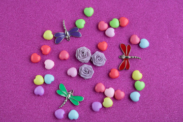 Colorful hearts,paper roses and dragonflies on a pink background.