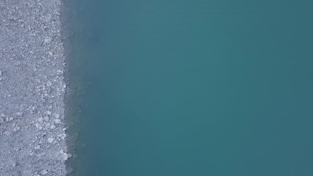 Plano cenital de drone de un lago con la orilla y el agua HD