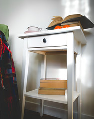 bedside table with books and wool plaid on the sofa