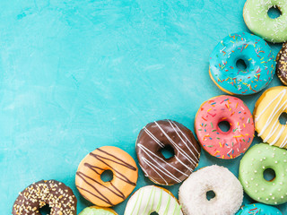 Top view of assorted donuts on blue concrete background with copy space. Colorful donuts...