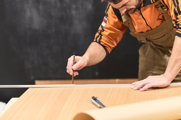 bearded man marking a wood with a pencil with a concentration face