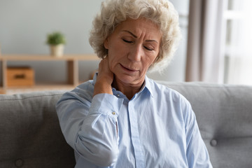 Fototapeta na wymiar Unhappy older woman massaging tensed neck muscles, feeling unwell