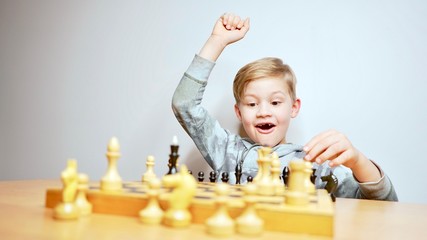 Happy boy playing chess. Caucasian child cheering while playing chess boardgame. White background 