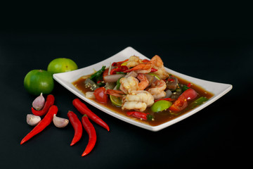 Thai Spicy papaya salad with shrimp, and hot chilli, Thai food in white dish on black background