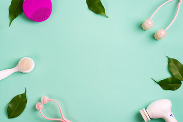 Frame of accessories for face care and green leaves. Clean skin with a different brush on a green background