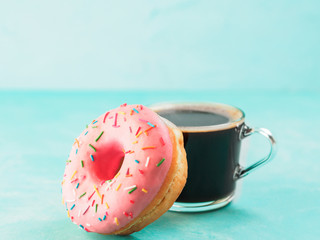 pink donut and coffee on blue background , copy space