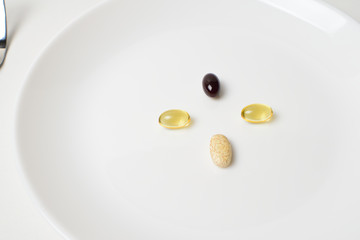 Multivitamin and mineral diet supplements. Astaxanthin.  Plate with tablets. Meal replacement. Closeup.