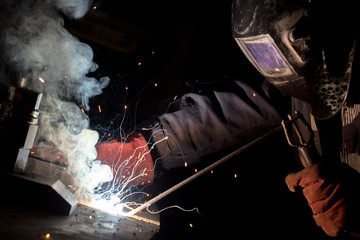 worker welds metal structures by electric arc welding