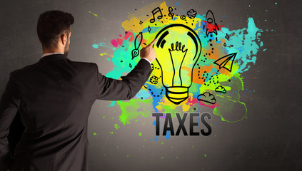businessman drawing colorful light bulb with TAXES inscription on textured concrete wall, new business idea concept
