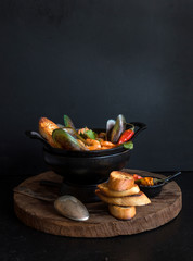 French fish soup Bouillabaisse with seafood, salmon fillet, shrimp on a black background....