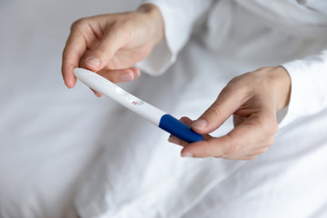 Close up young woman holding pregnancy test in hands