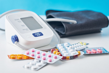 Digital blood pressure monitor and medical pills on the white table. Healthcare and medicine concept