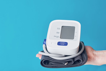 Digital blood pressure on the hand against blue background with copy space. Healthcare and medicine...