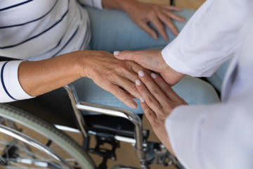 Top view close up caregiver holding disabled older woman hand