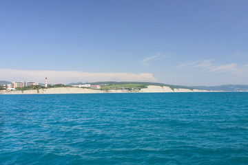 Coastal lighthouse on the edge of a rocky promontory in the black sea, the city of Gelendzhik. Located to the left of the frame. Landscape. Horizontal photo. Blurred background. Summer. opy space