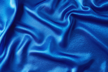 Blue silk background with a folds.  Abstract texture of rippled satin surface