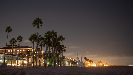 Night long exposure of the beach in Santa Monica with palms and some buildings in the background. Los Angeles, California