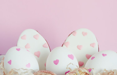 Easter white eggs with pink hearts, gingerbread in the form of eggs with hearts on a pink background..
