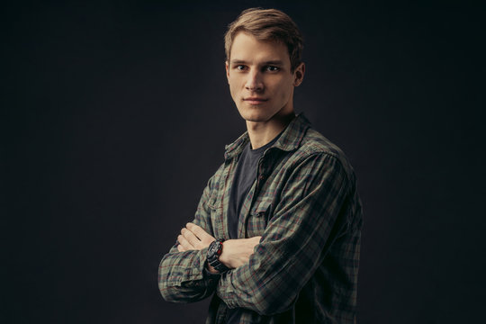 portrait of young caucasian man in checkered casual shirt stand isolated over black background. good-looking handsome make in studio