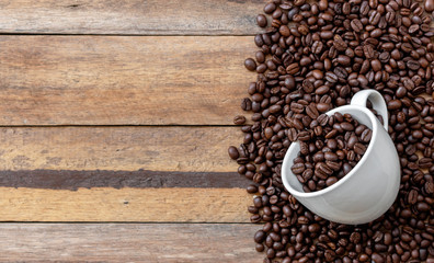 white cup and coffee bean on wooden background. top view