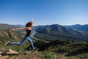 Fototapeta premium Portrait of a woman on top of a mountain on the background of the river flowing between the rocks.