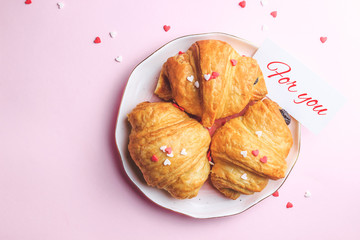 Valentine's day concept with two cups of coffee, almond croissant on pink plate on pink background. Top view,copy space. Romantic holiday