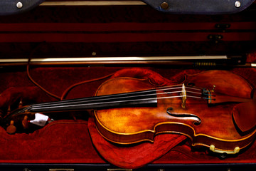 Fototapeta premium Violin in red velvet case. Classical wooden Violin in open red case. Top view. 