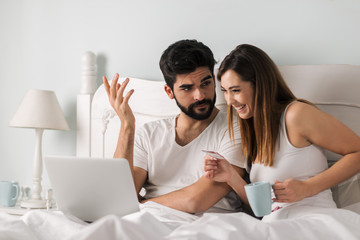 Happy woman is holding credit card while her boyfriend is displeased