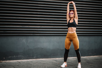 Portrait of fit and sporty sexy woman doing stretching in city urban landscape. Sport and fitness concept.