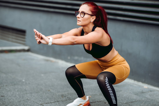 portrait of female woman doing squats training. Muscular woman doing cross fit workout outdoors