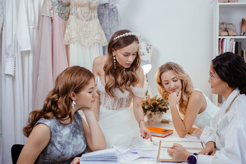 group caucasian models have conversation with designer and tailor of wedding dresses, have friendly...