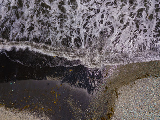 The black sand beach with blue stones in Flores island. Aerial view and top view. Beautiful natural backdrop. Indonesia