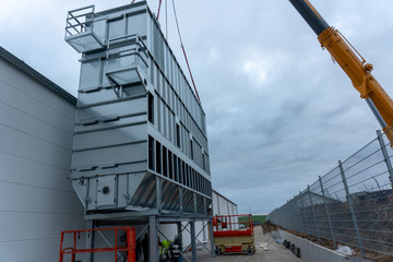 a huge extraction system for wood chips is installed on a factory building on a construction site