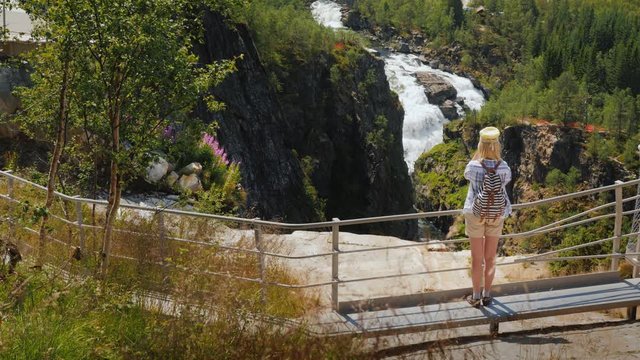 Woman taking pictures at the majestic waterfall of Woringsfossen in Norway. Impressive beauty of Scandinavian nature