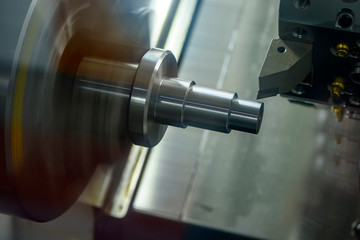 The CNC lathe machine in metal working process cutting the metal shaft parts with the cutting tools. The automotive parts production processing by CNC turning machine .