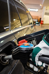 Fueling up a car with diesel at a service station with gloves on