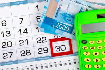 Obraz premium Calendar with a allocated 30 number, Russian two two-thousand bills, calculator