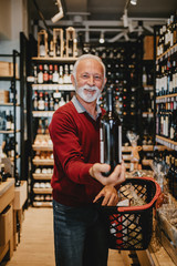 Happy senior man shopping in grocery store or supermarket. Consumerism concept.