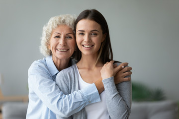 Head shot portrait happy caring grandmother hugging granddaughter